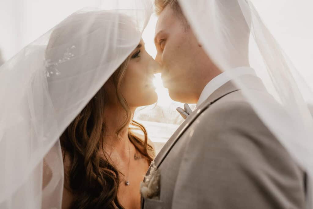 Braut und Bräutigam unter Hochzeitsveil, romantisches Paarfoto.