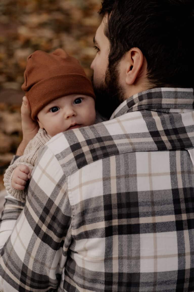 Vater hält Baby im Herbst, Natur, Blätter, Familienmoment.