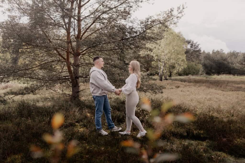 Verlobtes Paar hält Händchen im Naturpark bei Sonnenuntergang.