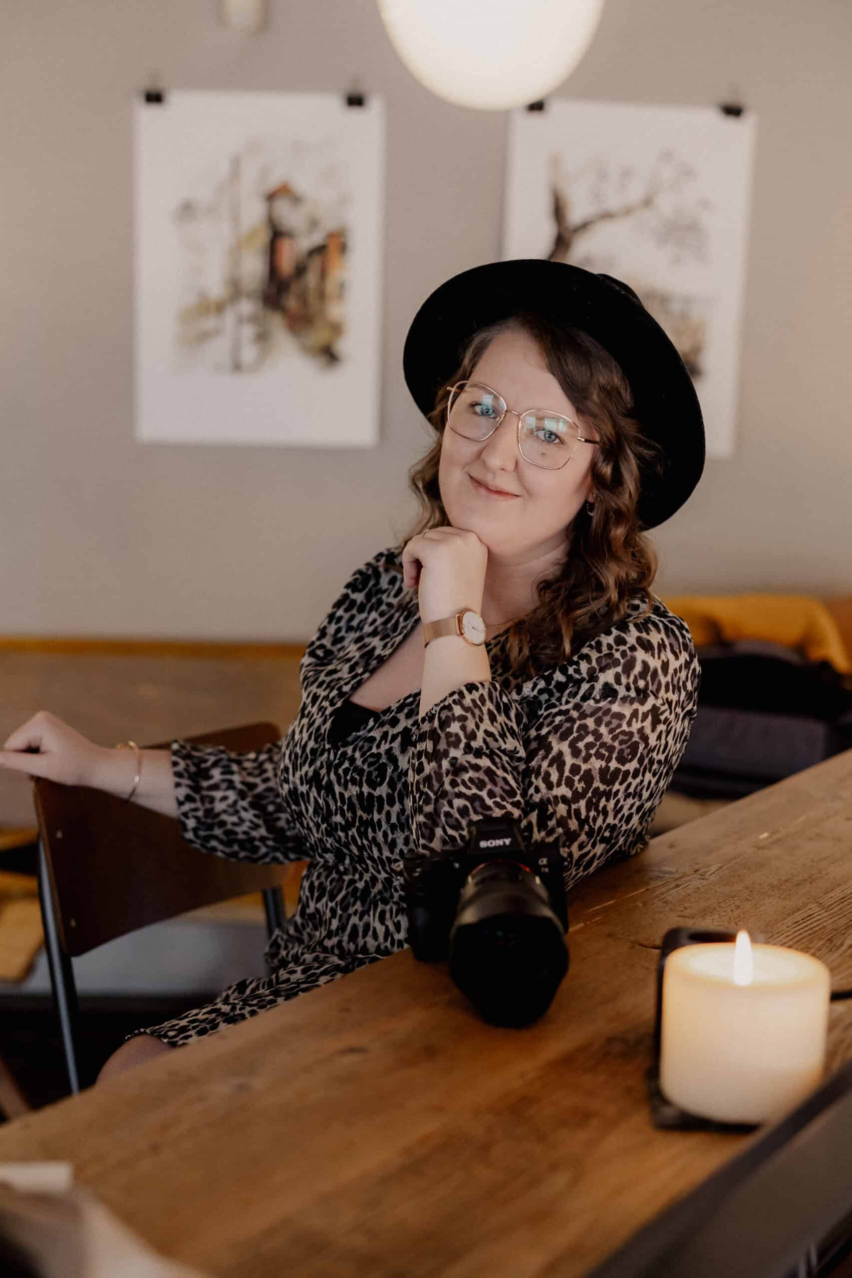 Miriam Weimer, Hochzeitsfotografin, mit Kamera und Brille, im gemütlichen Raum.