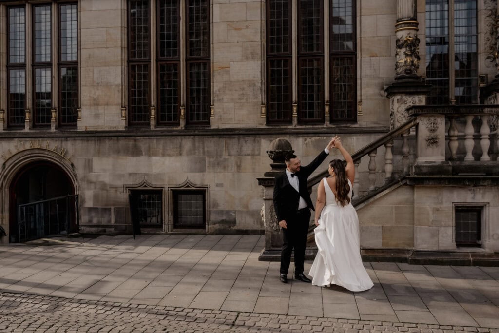 Verliebtes Brautpaar tanzt vor historischem Gebäude in Bremen.