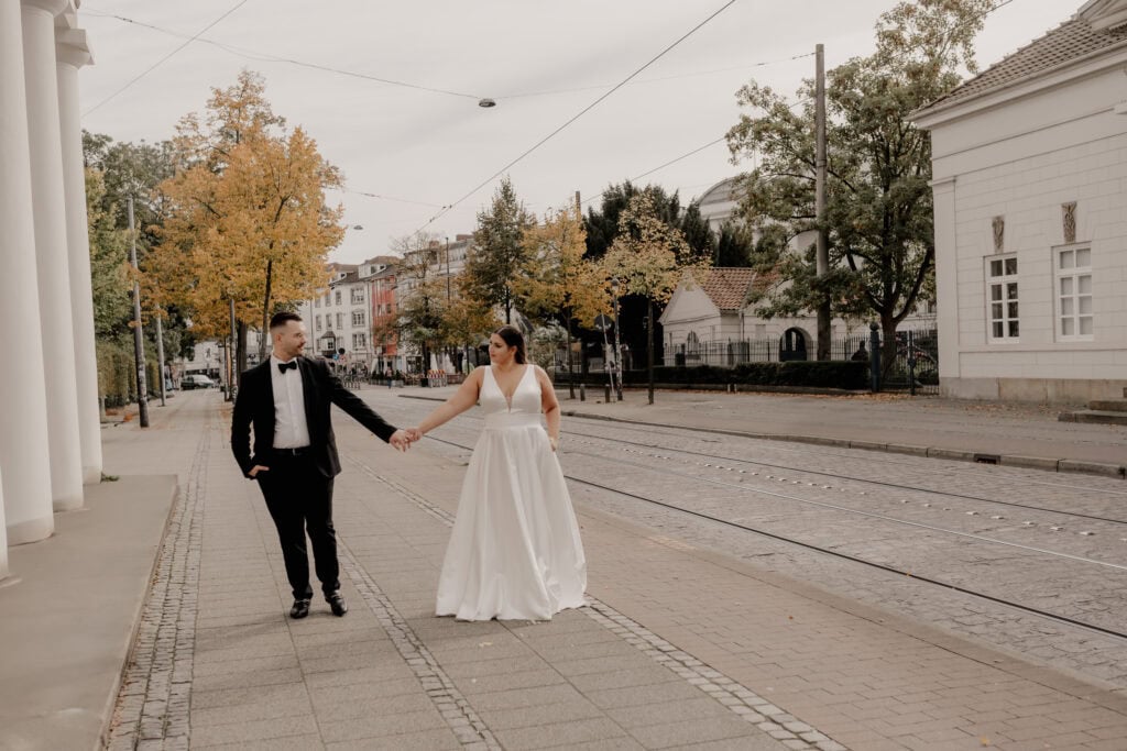 Braut und Bräutigam halten Händchen auf der Straße in Bremen.