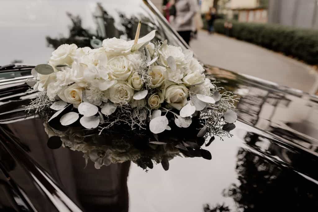 Hochzeitsauto mit weißem Blumenbouquet auf dem Dach.