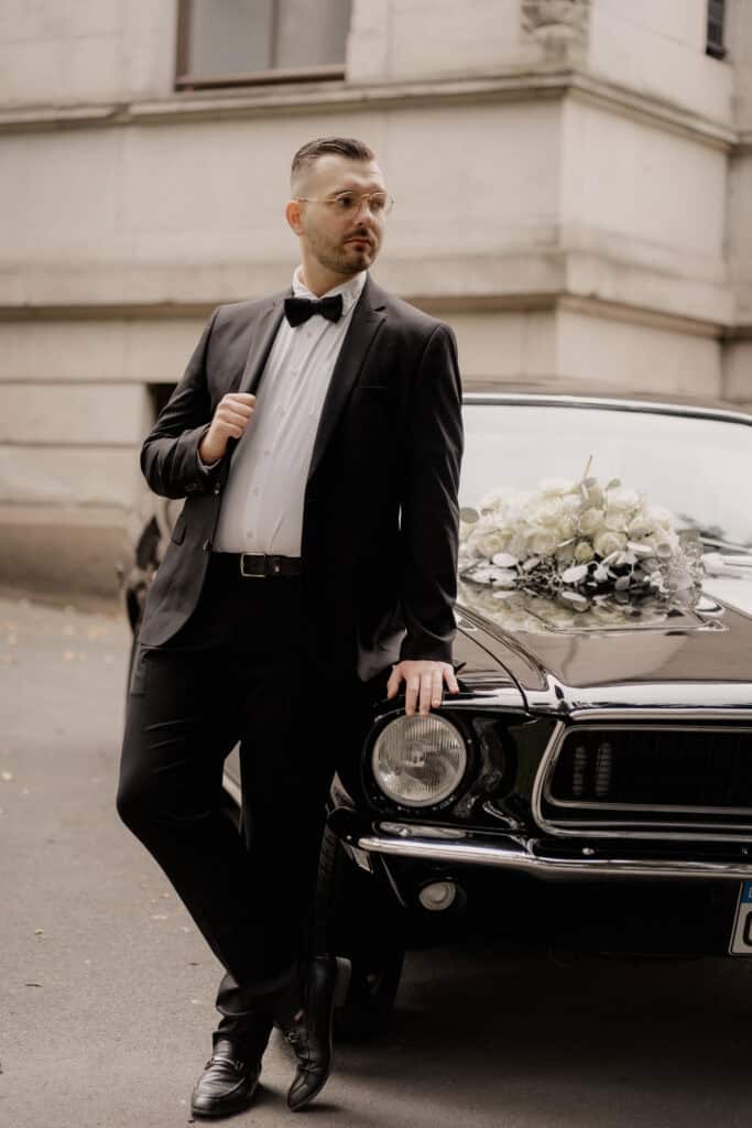 Stilvoller Mann in Anzug mit Fliege neben Oldtimer bei Insposhooting Bremen.