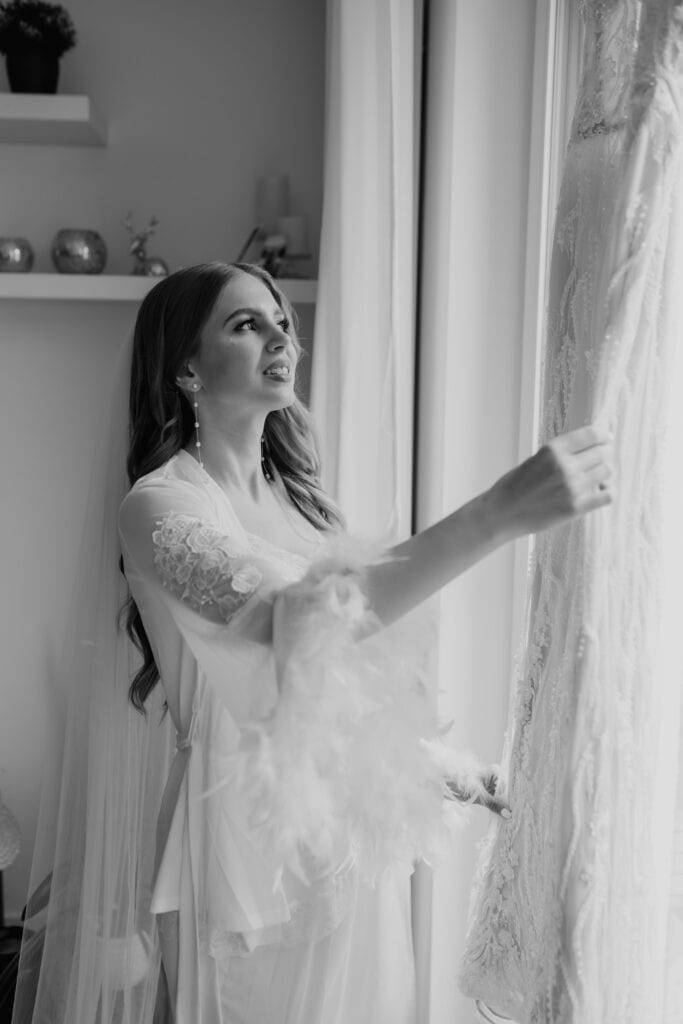 Miriam Weimer schaut aus dem Fenster, in Hochzeitskleid, bei Sonnenlicht.