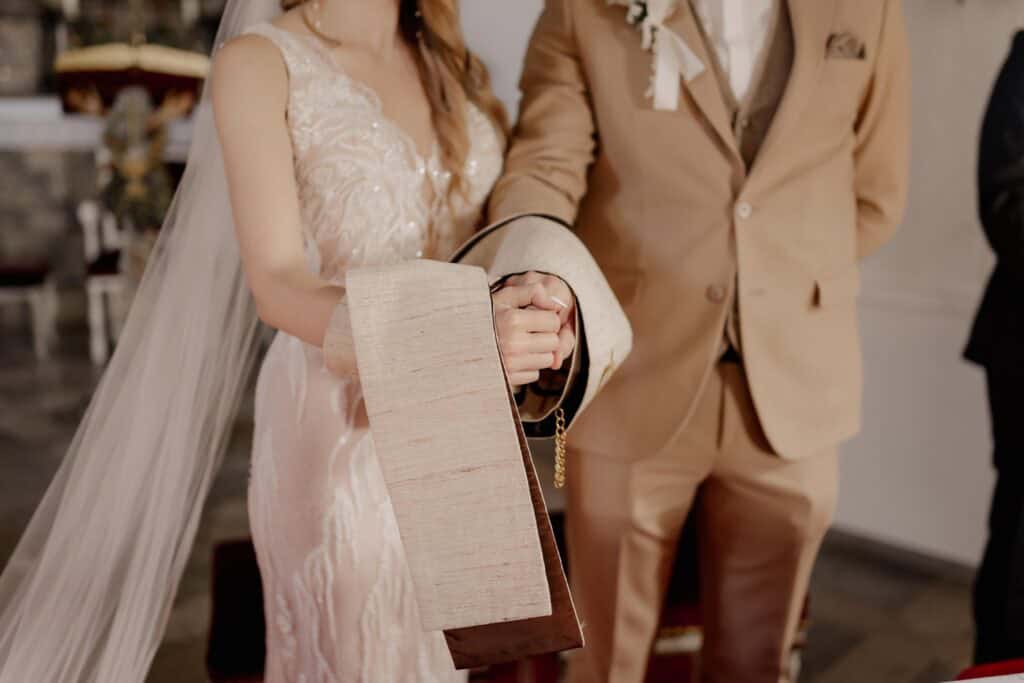 Hochzeitspaar bei Zeremonie, Fokus auf Hände und Brautkleid.