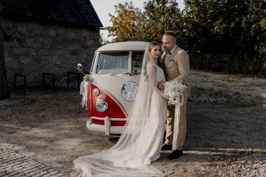 Braut und Bräutigam vor einem Vintage VW Bus bei Hochzeit.