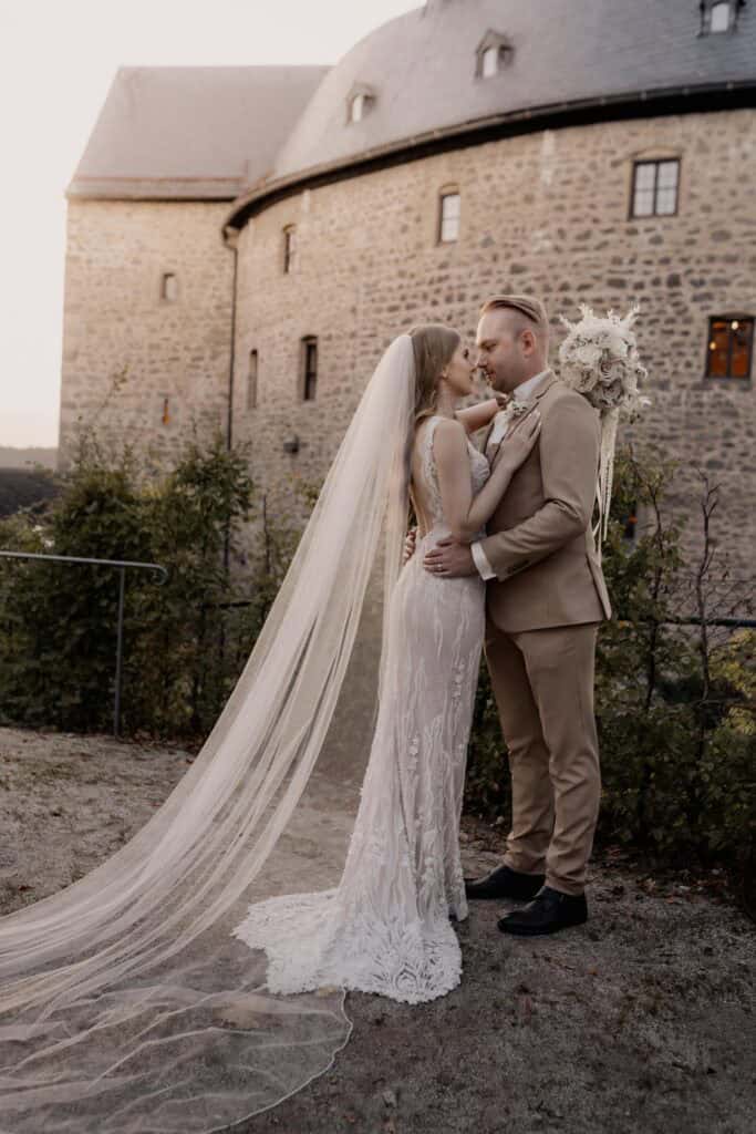 Braut und Bräutigam bei ihrer Hochzeit vor einer Burg.