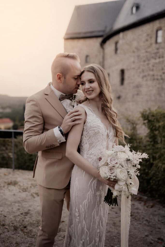 Braut und Bräutigam bei ihrer Hochzeit vor einer Burg.