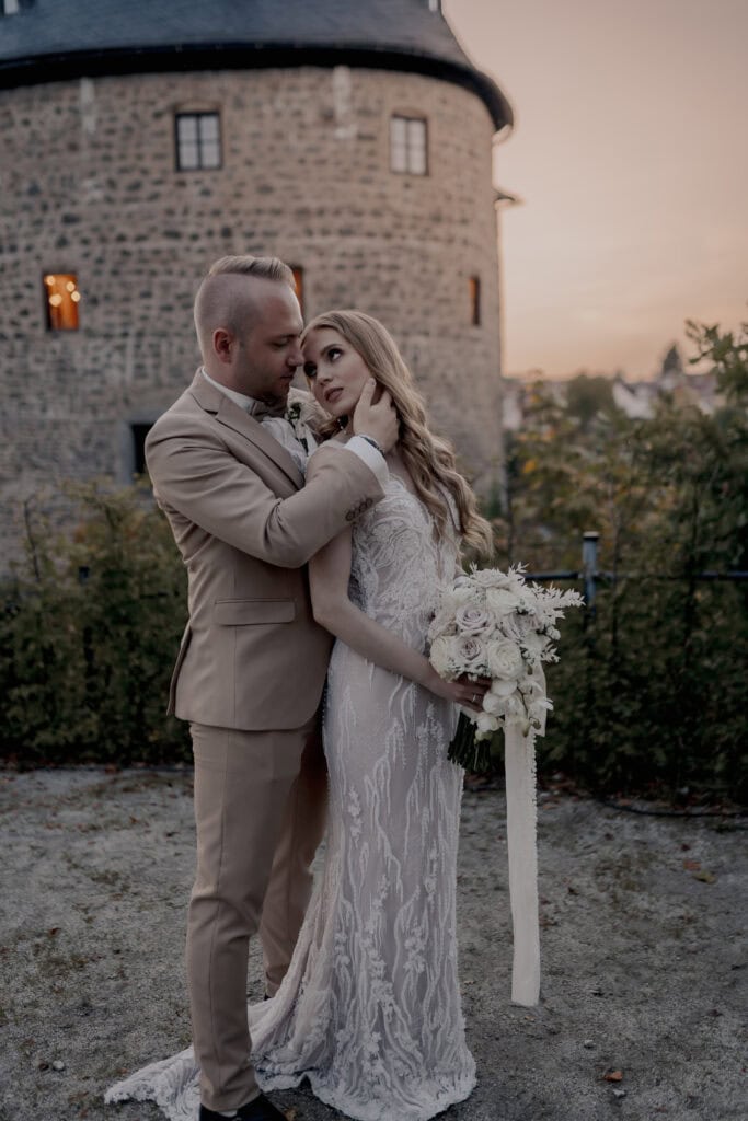 Braut und Bräutigam bei Hochzeit vor Burg im Sonnenuntergang.
