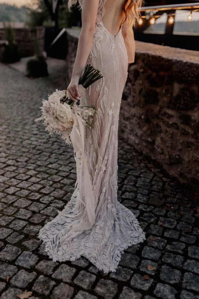Braut in eleganten Hochzeitskleid mit Blumenstrauß bei Viola & Valentin.