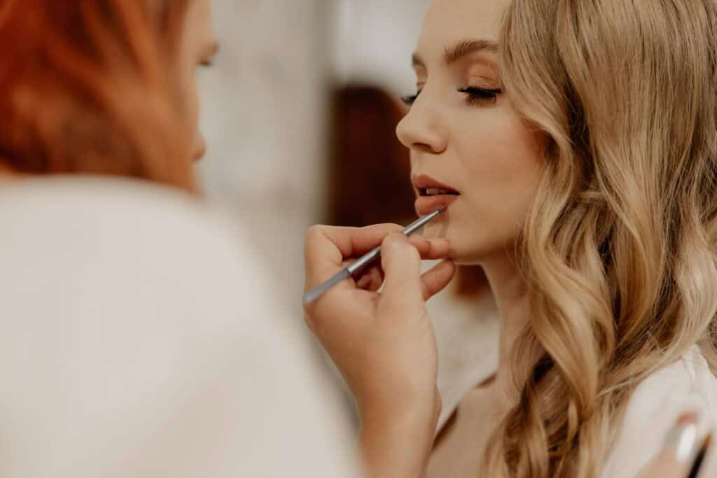 Braut wird für Hochzeit geschminkt, professionelle Make-up-Künstlerin bei der Arbeit.