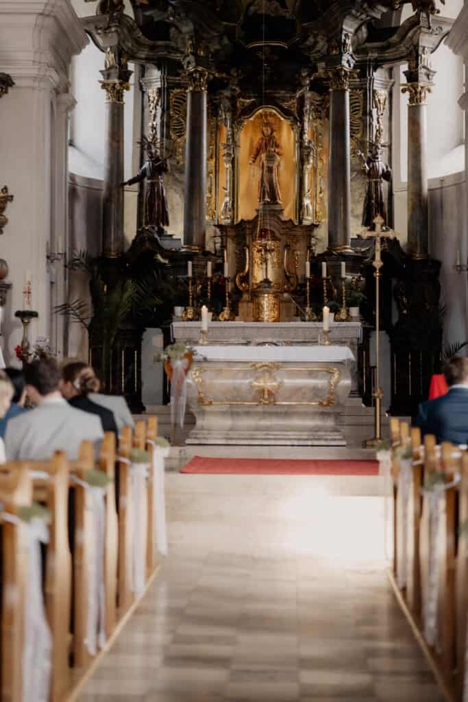 Innenaufnahme einer barocken Kirche bei einer Hochzeit mit Blick auf den Altar.