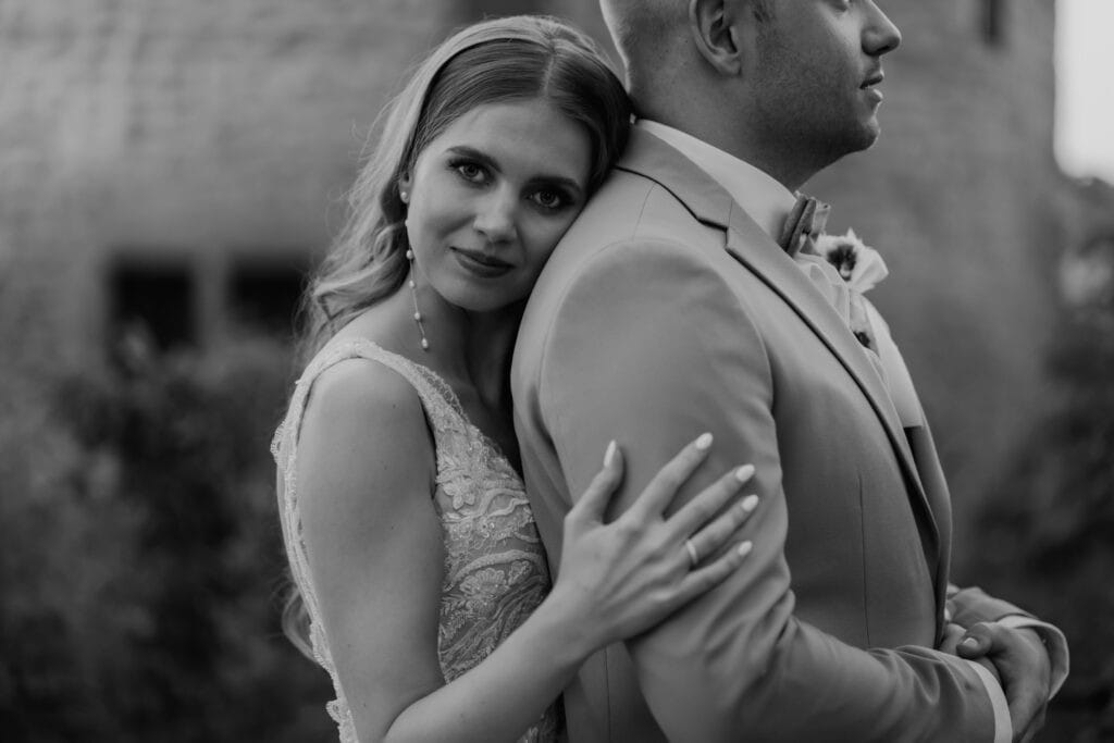 Braut umarmt Bräutigam bei Hochzeit, emotionaler Moment.