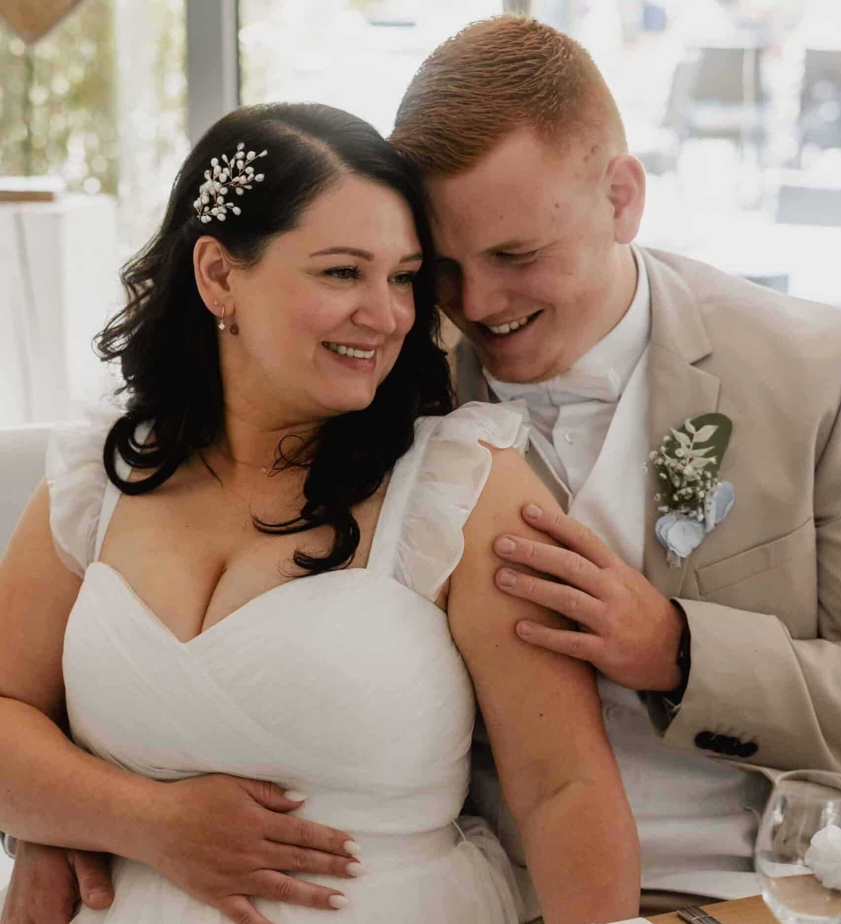 Glückliches Brautpaar bei einer Hochzeit, lachend und umarmend.