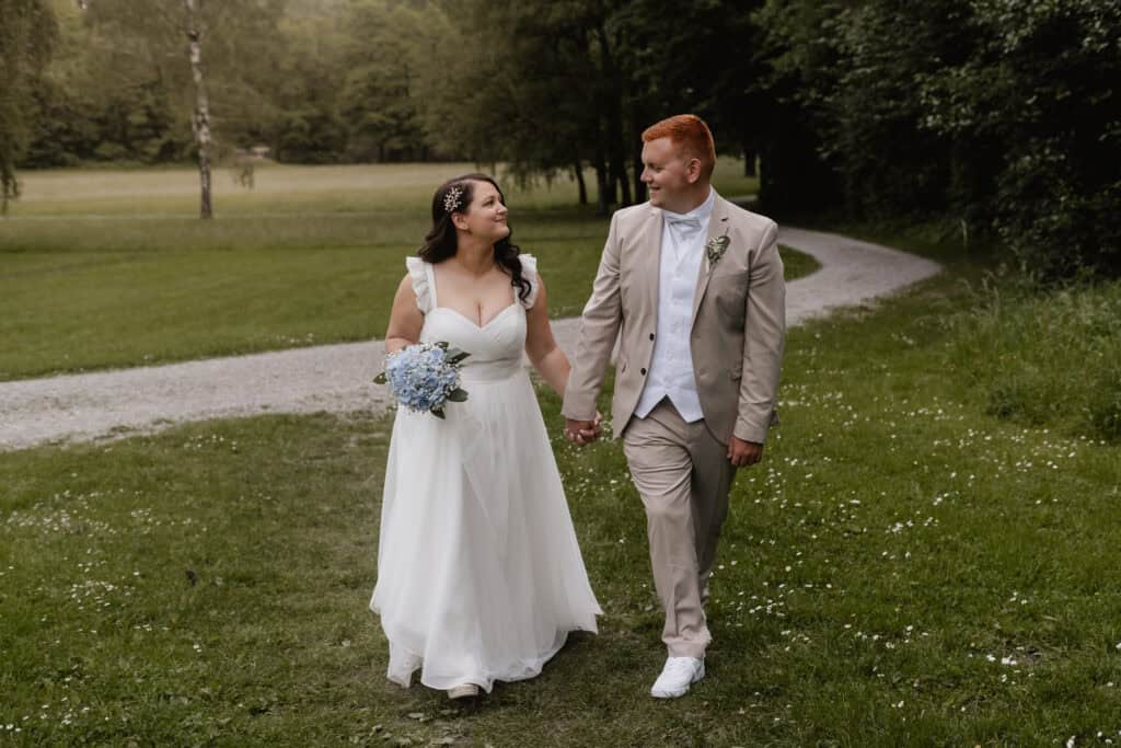 Braut und Bräutigam beim Spaziergang im Park an ihrem Hochzeitstag.