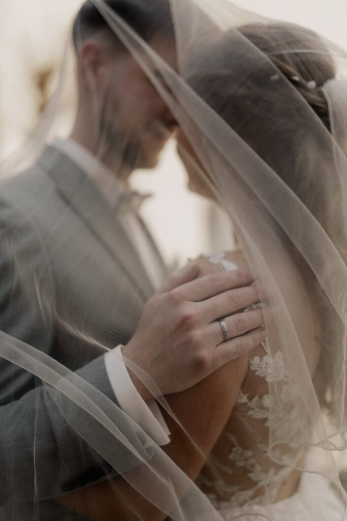 Hochzeitspaar unter Brautstrauß, romantisch und emotional.