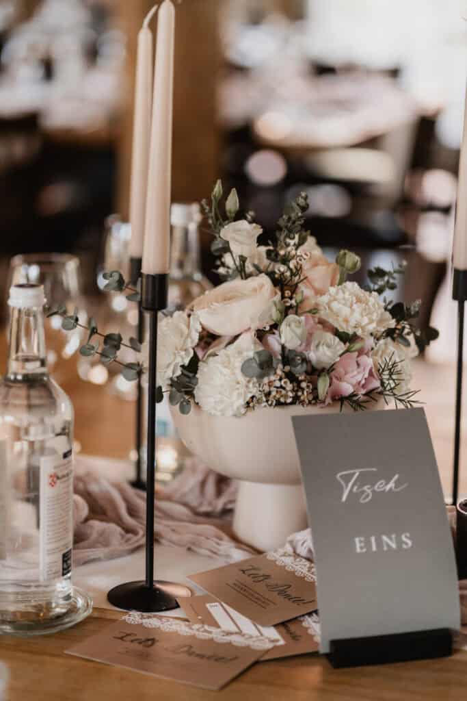 Elegante Tischdekoration mit Blumen, Kerzen und Platzkarten bei einer Hochzeit.