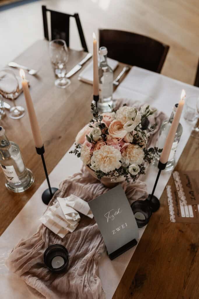 Eleganter gedeckter Tisch mit Blumen, Kerzen und Getränken für eine Hochzeit.