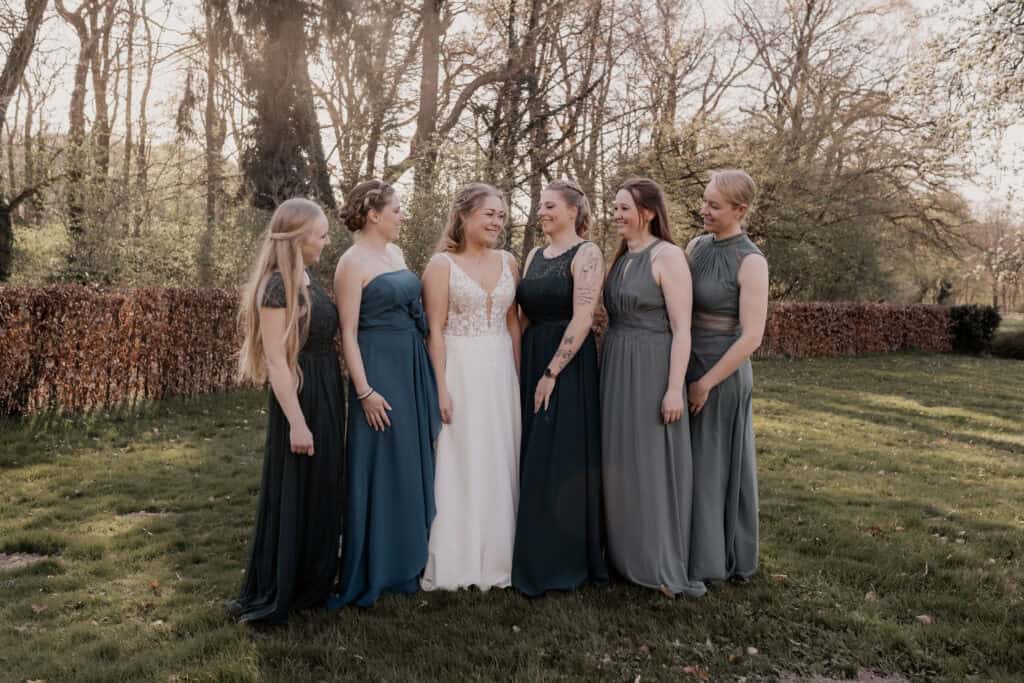 Hochzeitsgruppe mit Braut und Freundinnen im Park bei Sonnenuntergang.