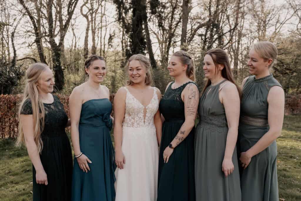 Hochzeitsgruppe mit Braut und Freundinnen im Park bei Sonnenuntergang.