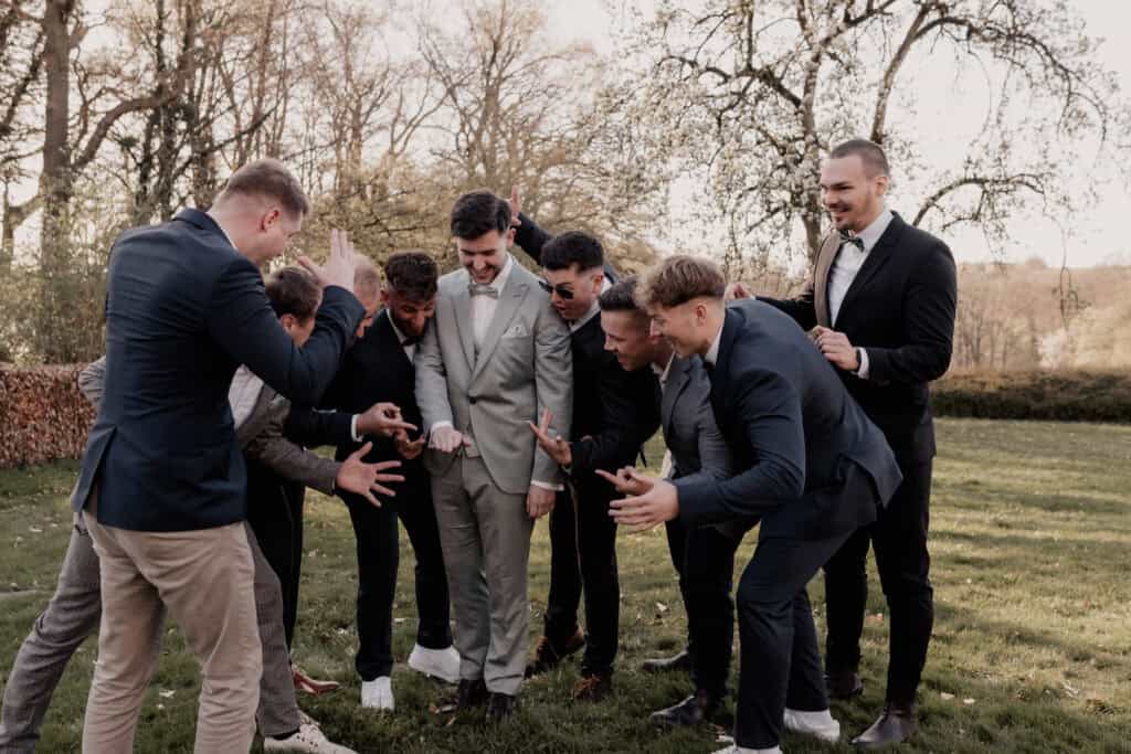 Junge Männer in Anzügen beim Outdoor-Event, fröhlich und lachend.