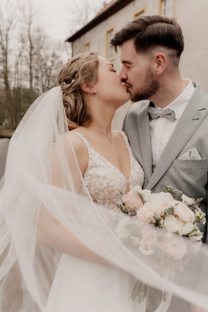 Braut und Bräutigam küssen sich bei Hochzeit im Freien.
