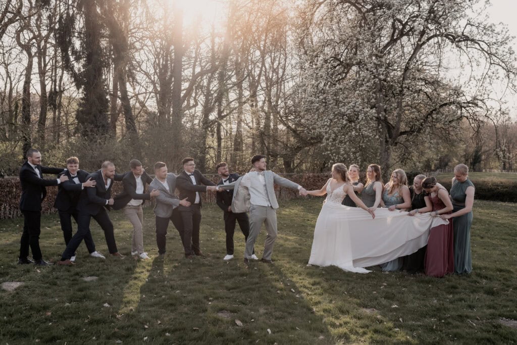 Hochzeitsszene mit Braut, Bräutigam und Hochzeitsgästen im Park bei Sonnenuntergang.