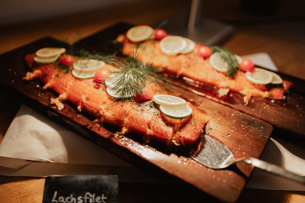 Lachsfilet mit Zitronenscheiben und Dill auf Holzplatte.