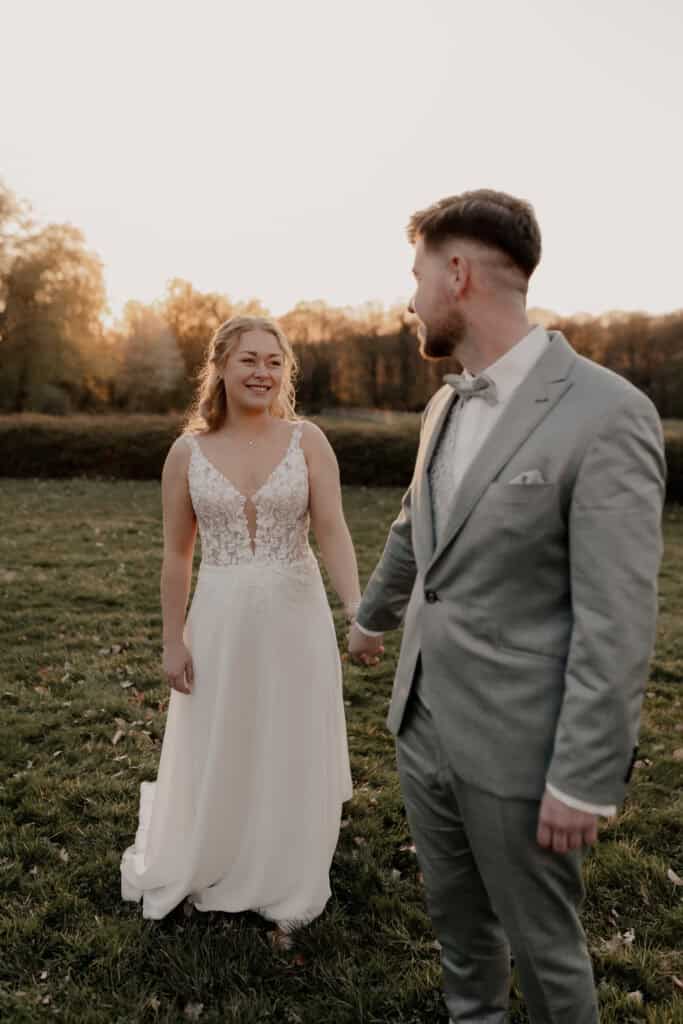 Braut und Bräutigam halten Händchen im Sonnenuntergang bei ihrer Hochzeit.