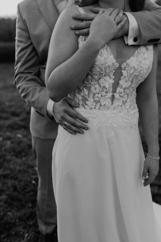 Hochzeitspaar in Umarmung, Braut in elegantes Kleid, romantisches Paarfoto.