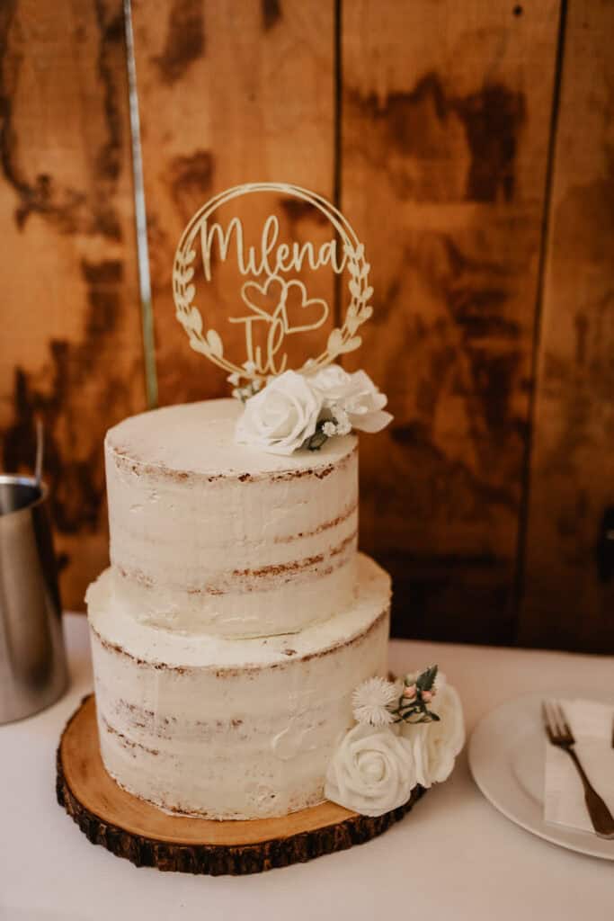 Hochzeitstorte mit Blumen und personalisiertem Tortenstecker.