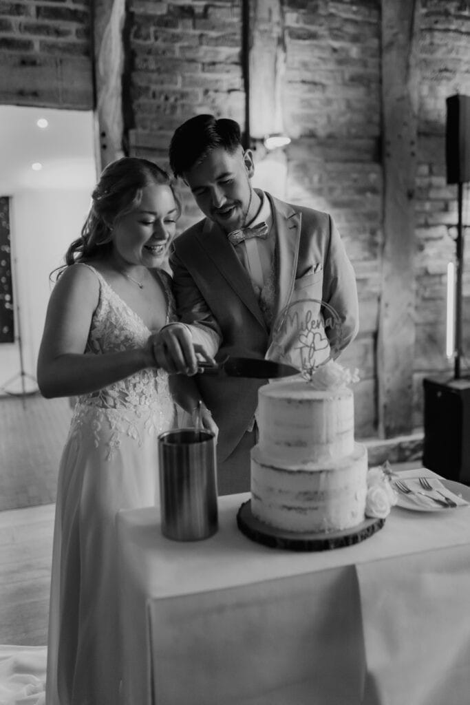 Braut und Bräutigam schneiden Hochzeitstorte bei ihrer Feier.