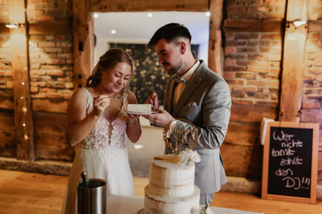 Hochzeitspaar beim Anschneiden der Torte, romantische Atmosphäre.