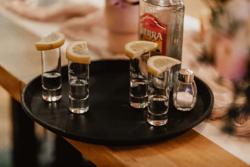 Shots mit Zitronenscheiben auf einem schwarzen Teller.