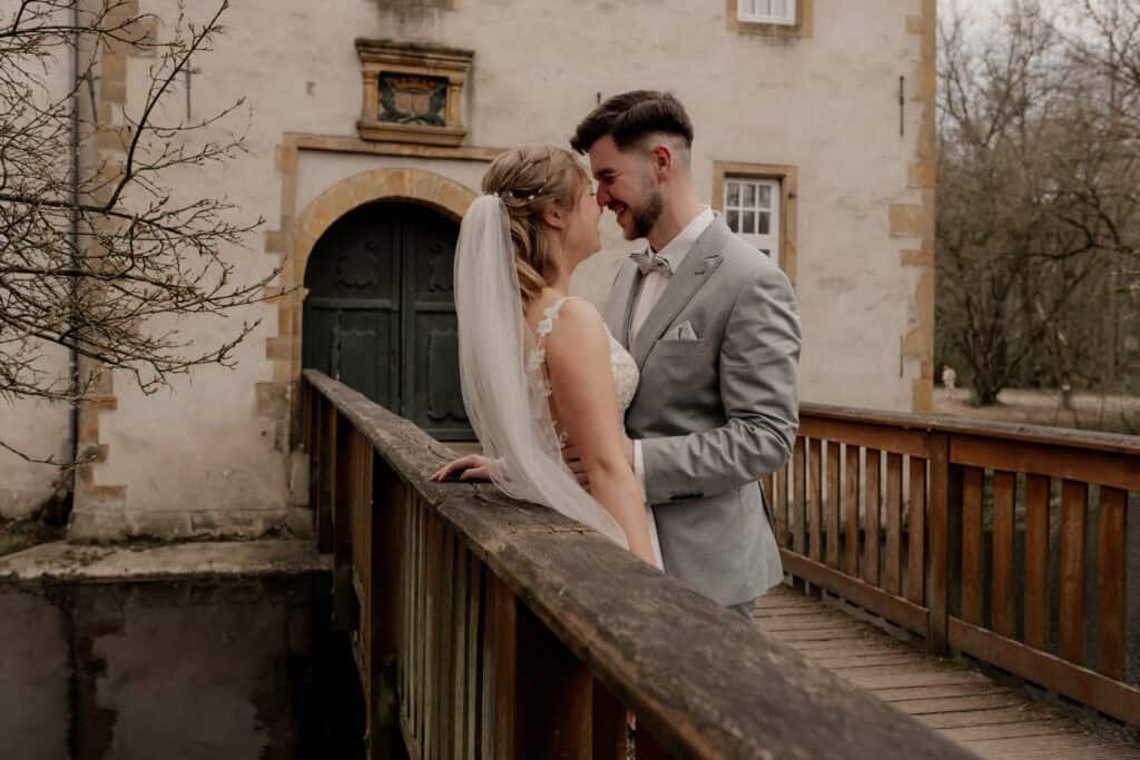 Braut und Bräutigam auf Brücke bei Hochzeit im Freien.