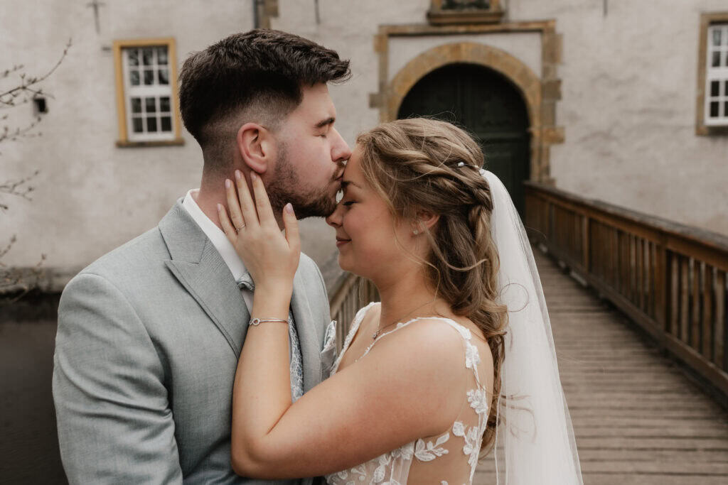 Braut und Bräutigam küssen sich bei Hochzeit im Freien.