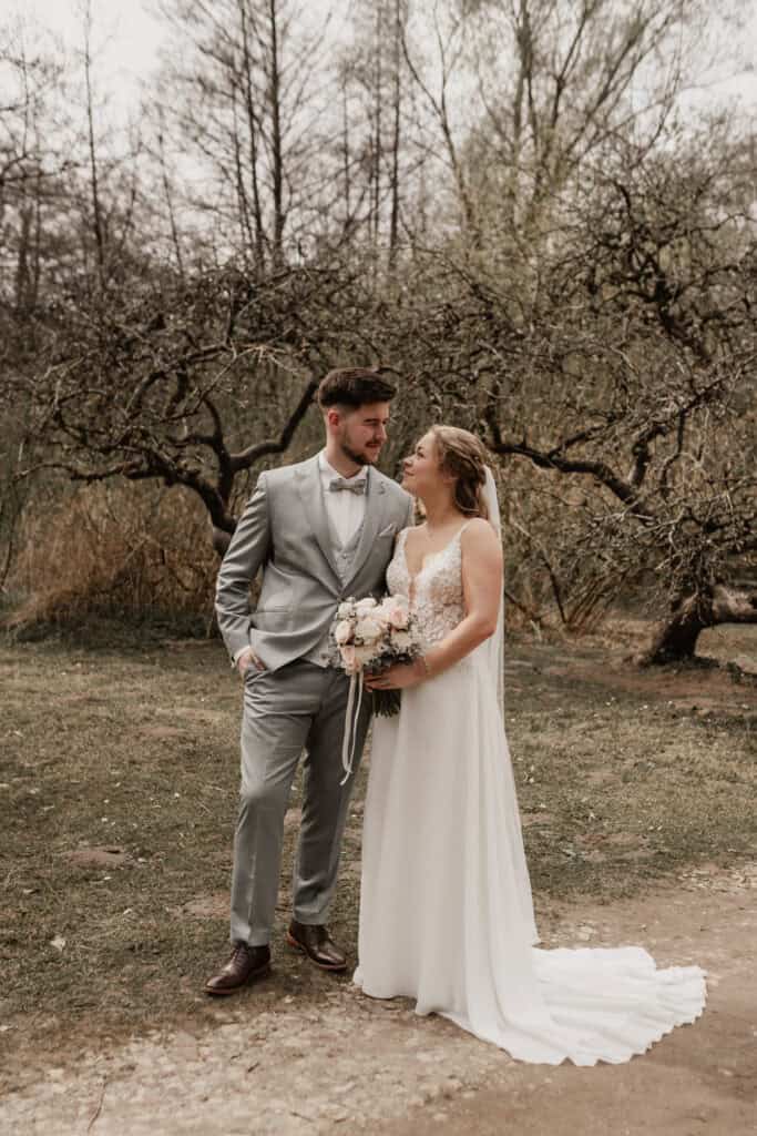 Hochzeitspaar im Freien, Braut und Bräutigam in eleganten Outfits.