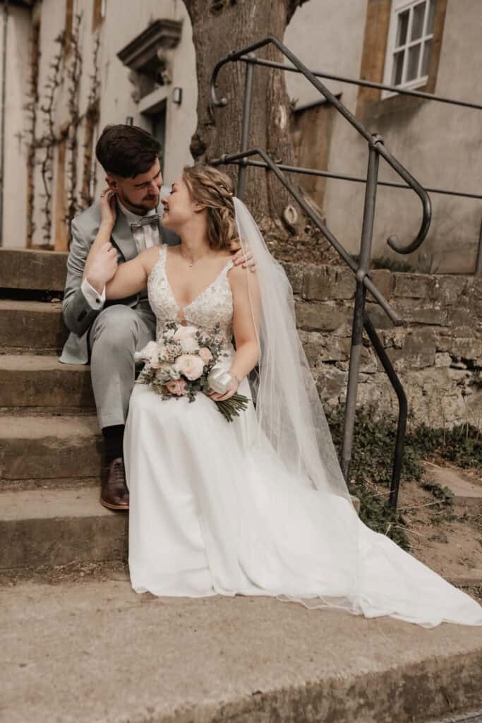 Braut und Bräutigam bei ihrer Hochzeit auf den Stufen im Freien.