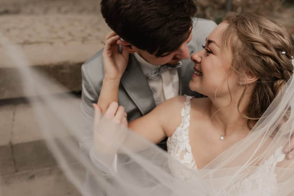 Braut und Bräutigam lachen sich an, romantisches Hochzeitsfoto am Strand.