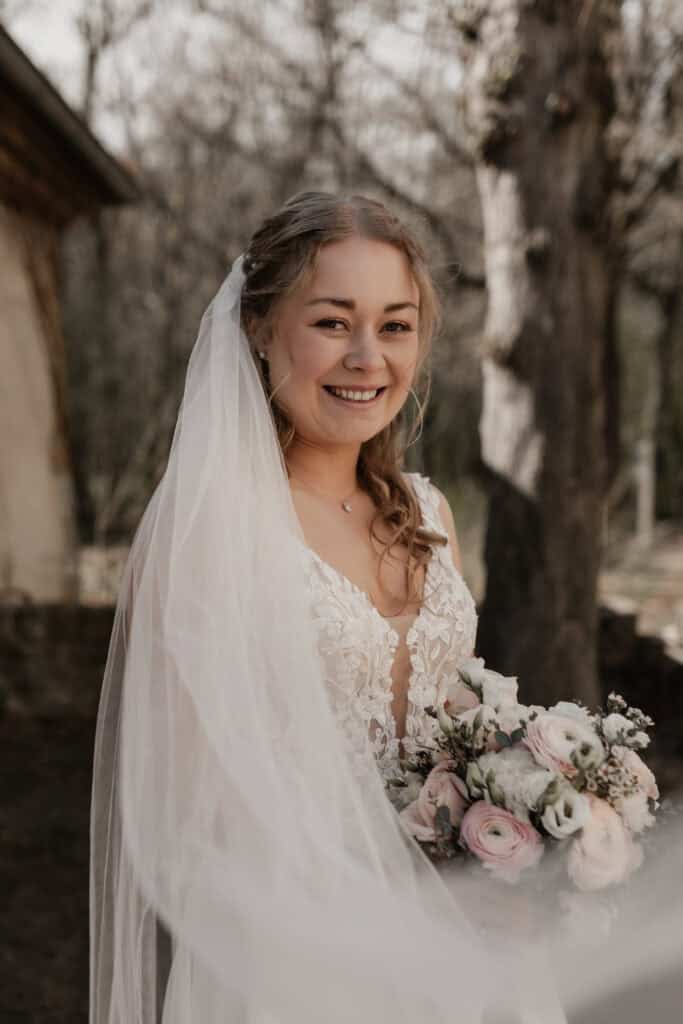 Braut mit Blumenstrauß bei Hochzeit im Freien, natürliche Umgebung.