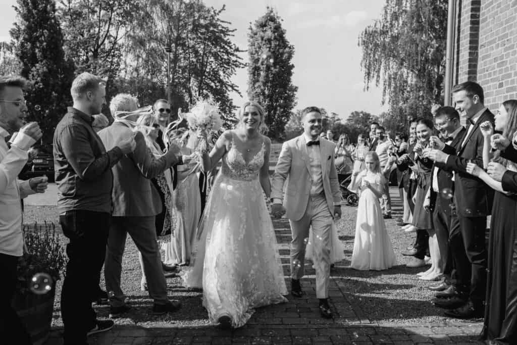 Hochzeitspaar bei der Feier, umgeben von Gästen im Freien.