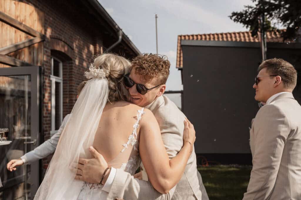 Hochzeitspaar umarmt sich bei sonnigem Wetter im Garten.