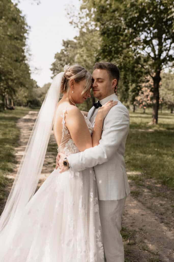 Braut und Bräutigam umarmend im Park bei Hochzeit.