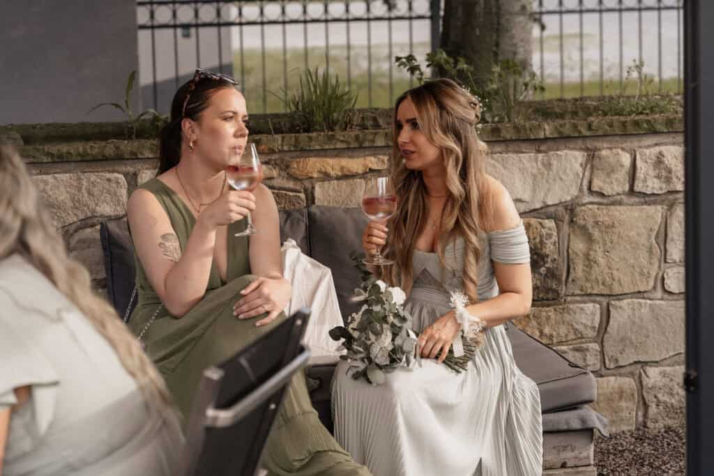 Zwei Frauen bei einer Hochzeit stoßen mit Wein an.