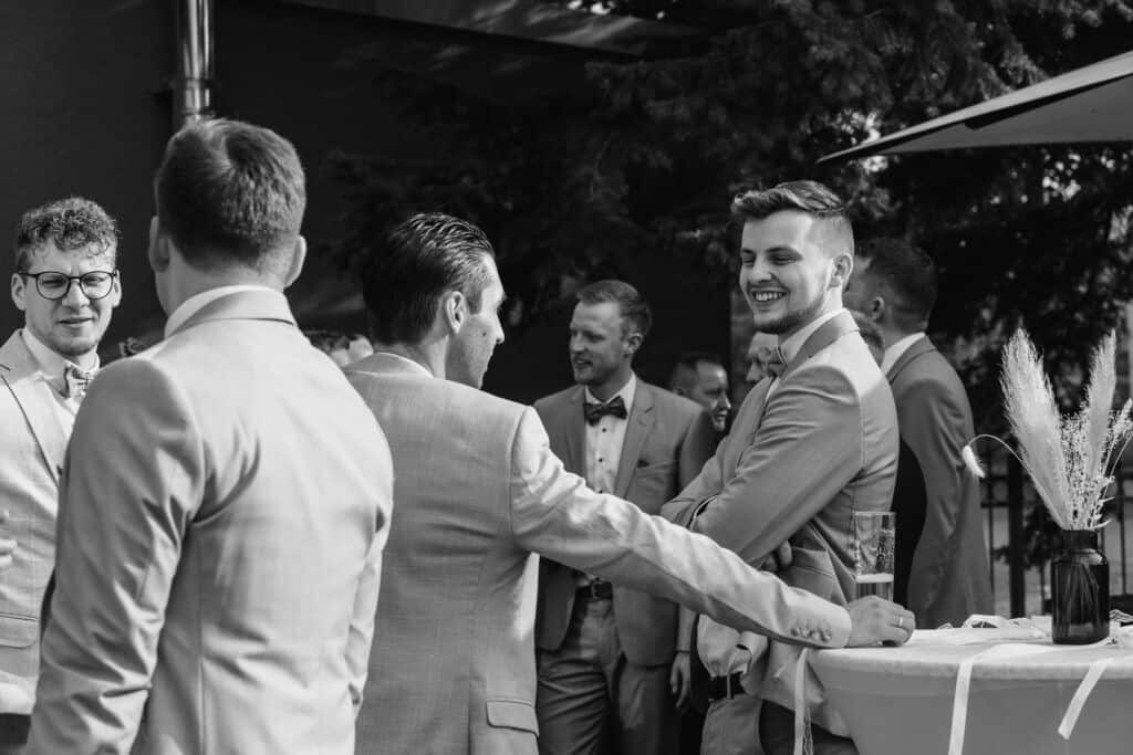 Hochzeitsparty mit lachenden Gästen bei einer Feier im Freien.
