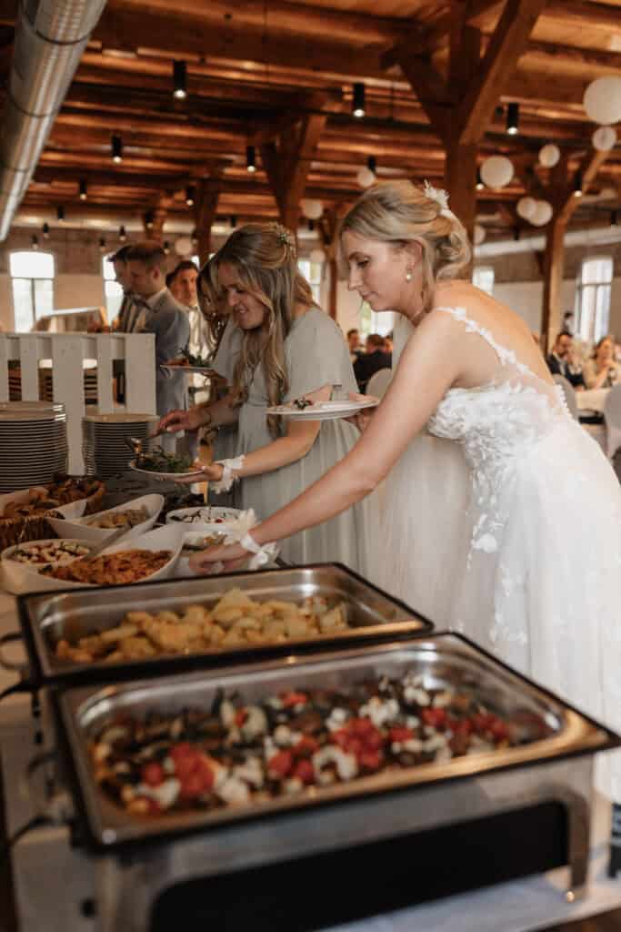 Braut beim Buffet bei einer Hochzeit in einer rustikalen Location.