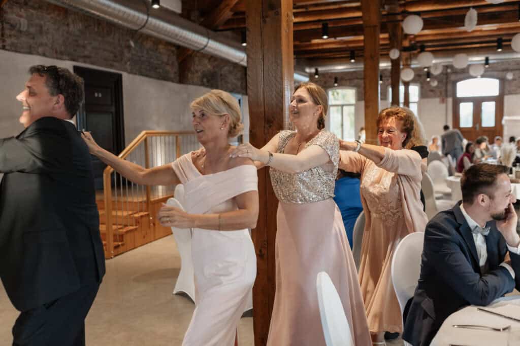 Hochzeitstanz mit lachenden Gästen in festlicher Atmosphäre.