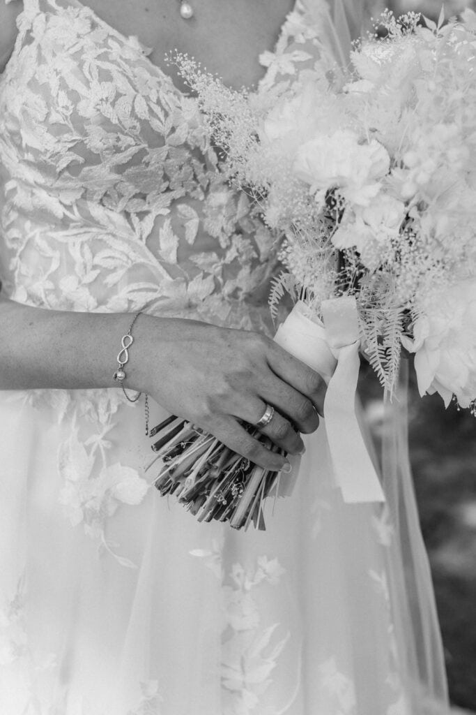 Braut hält Blumenstrauß bei Hochzeit, Nahaufnahme in Schwarz-Weiß.