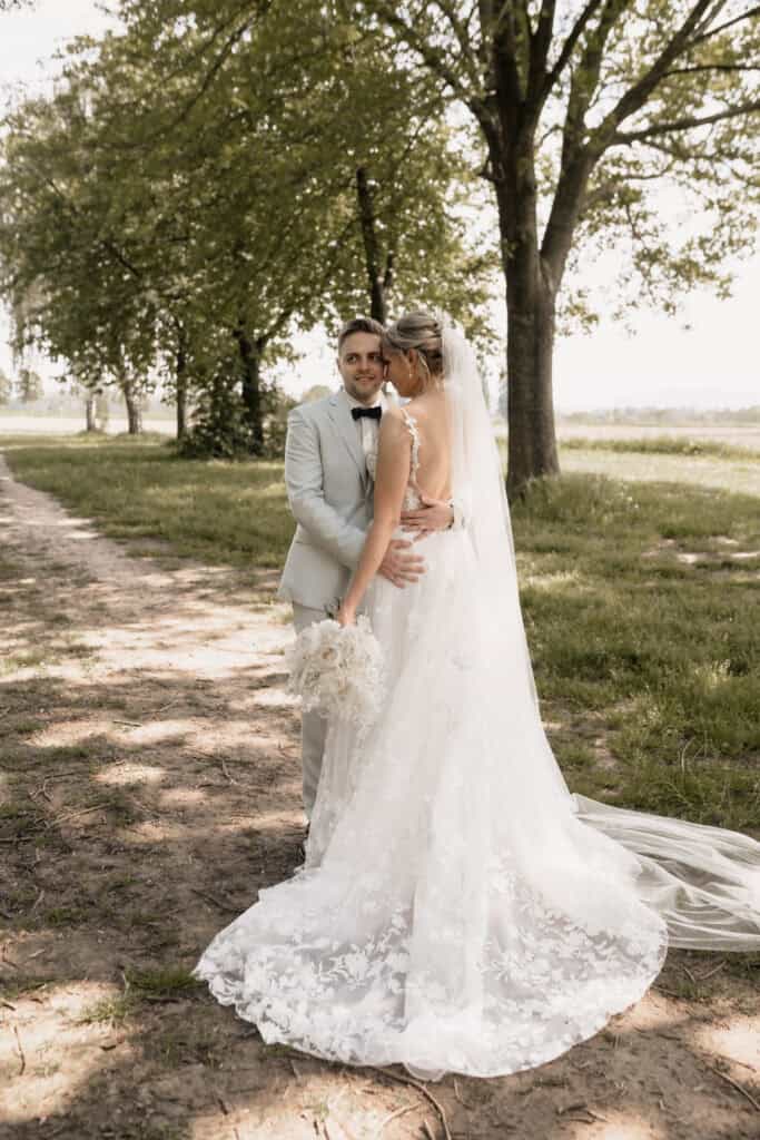 Hochzeitspaar im Park, Braut in weißem Kleid, Bräutigam in Anzug, Naturkulisse.